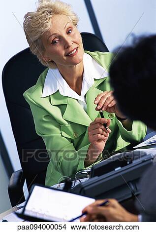 Businesswoman listening to colleague, blurred foreground View Large Photo Image Picture - Businesswoman listening to colleague, blurred foreground. Fotosearch