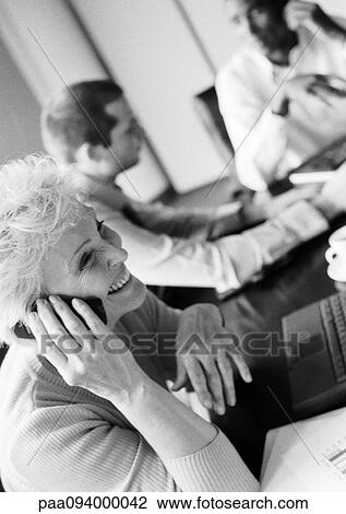 Businesswoman using cell phone in conference room, colleagues in blurred background, B&W View Large Photo Image Stock Image - Businesswoman using cell phone in conference room, colleagues in blurred background, B&W. Fotosearch