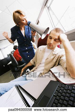 Businesswoman using megaphone to wake up sleeping colleague View Large Photo Image Stock Photo - Businesswoman using megaphone to wake up sleeping colleague. Fotosearch