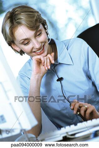 Businesswoman wearing headset at desk View Large Photo Image Stock Photo - Businesswoman wearing headset at desk. Fotosearch