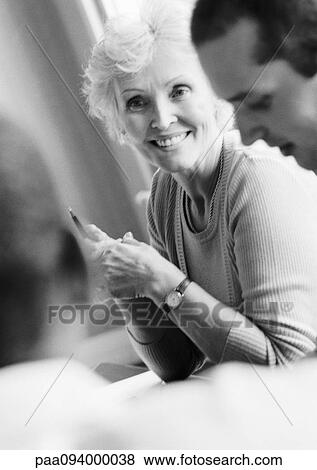 Mature businesswoman in conference, smiling, with two colleagues, B&W View Large Photo Image Stock Photo - Mature businesswoman in conference, smiling, with two colleagues, B&W. Fotosearch