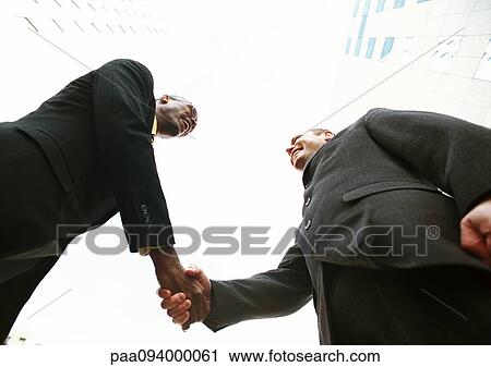 Two businessmen shaking hands, low angle view View Large Photo Image Stock Image - Two businessmen shaking hands, low angle view. Fotosearch