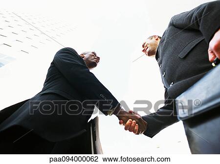 Two businessmen shaking hands, low angle view View Large Photo Image Stock Image - Two businessmen shaking hands, low angle view. Fotosearch