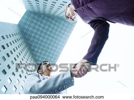 Two businesswomen shaking hands, low angle view View Large Photo Image Picture - Two businesswomen shaking hands, low angle view. Fotosearch