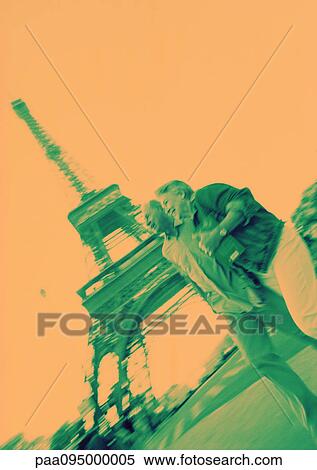Stock Photography - France, Paris, mature woman and man in front of Eiffel Tower, orange and green tones. Fotosearch