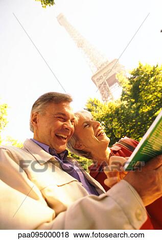 France, Paris, mature woman and man holding a book and laughing, Eiffel Tower in background View Large Photo Image Stock Photo - France, Paris, mature woman and man holding a book and laughing, Eiffel Tower in background. Fotosearch