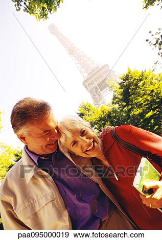 Stock Photo - France, Paris, mature woman and man smiling, Eiffel Tower in background, portrait. Fotosearch