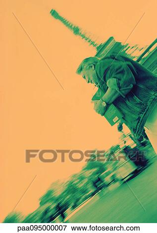 Stock Photo - France, Paris, mature woman in front of Eiffel Tower, orange and green tones. Fotosearch