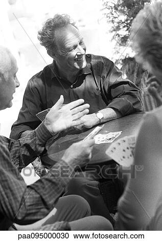 Stock Image - Mature adults playing cards, B&W. Fotosearch