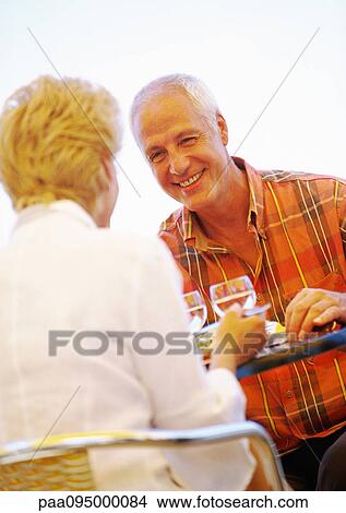 Picture - Mature man and woman having a meal together, close-up. Fotosearch