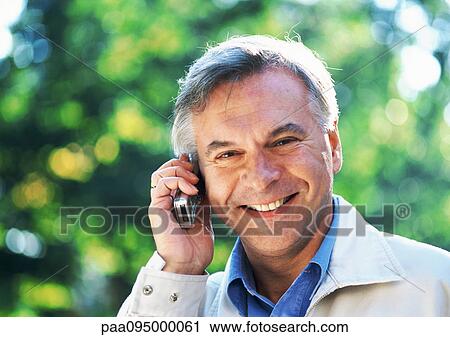 Stock Image - Mature man with cell phone, close-up, portrait. Fotosearch