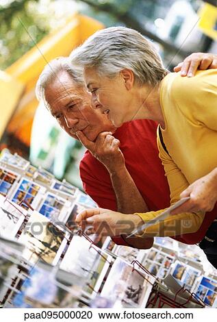 Stock Image - Mature woman and man looking at postcards. Fotosearch