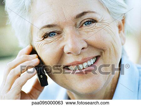 Stock Image - Mature woman with cell phone, close-up, portrait. Fotosearch