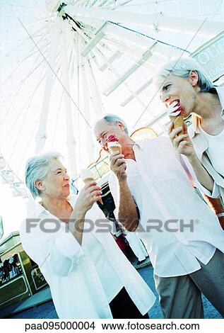Mature women and man eating ice cream in amusement park View Large Photo Image Picture - Mature women and man eating ice cream in amusement park. Fotosearch