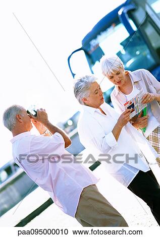 Two mature women looking at map, mature man taking photo View Large Photo Image Stock Image - Two mature women looking at map, mature man taking photo. Fotosearch