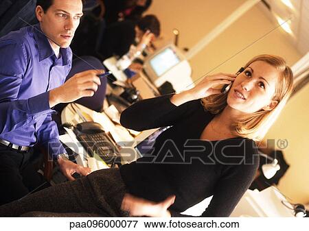 Stock Photo - Man looking at woman talking on telephone in office. Fotosearch