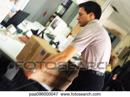 Stock Photo - Man placing box on desk, blurred. Fotosearch