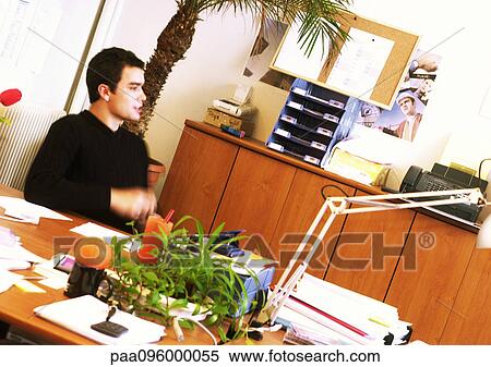 Man sitting at desk in office, side view View Large Photo Image Stock Photography - Man sitting at desk in office, side view. Fotosearch