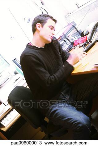 Stock Image - Man sitting at desk in office. Fotosearch