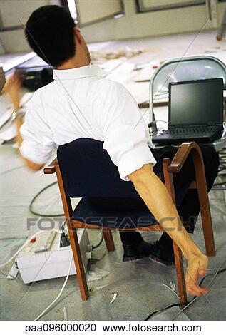 Man sitting in chair stretching arms, in front of laptop computer on chair View Large Photo Image Stock Image - Man sitting in chair stretching arms, in front of laptop computer on chair. Fotosearch