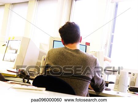 Stock Image - Man working at computer, rear view. Fotosearch