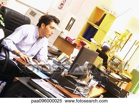 Man working at desk in office View Large Photo Image Stock Photography - Man working at desk in office. Fotosearch