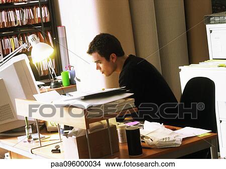 Man working at desk, side view View Large Photo Image Picture - Man working at desk, side view. Fotosearch