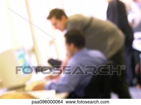Picture - Men looking at computer in office, side view, blurred. Fotosearch