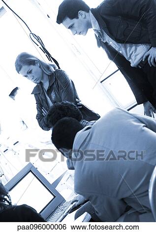 People standing around computer in office View Large Photo Image Stock Photograph - People standing around computer in office. Fotosearch