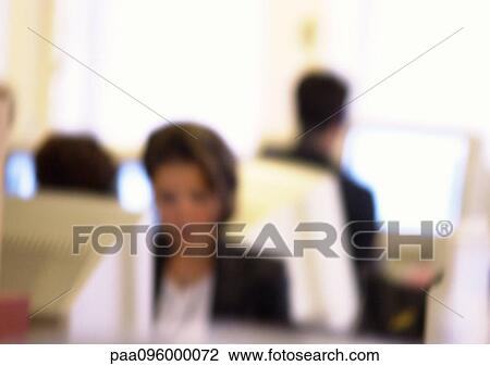 Stock Image - People working at computers in office, blurred. Fotosearch