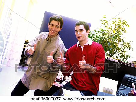 Two men in office giving thumbs up, looking at camera, portrait View Large Photo Image Stock Photo - Two men in office giving thumbs up, looking at camera, portrait. Fotosearch