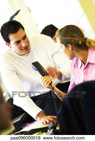 Woman handing telephone to man in office View Large Photo Image Stock Photo - Woman handing telephone to man in office. Fotosearch
