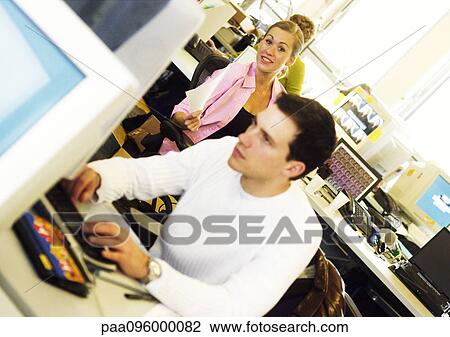 Stock Image - Woman smiling, man working on computer in office. Fotosearch