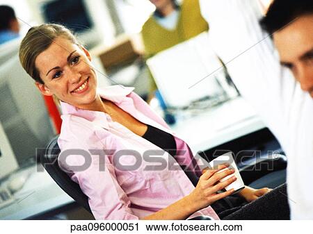 Woman smiling toward co-worker in office View Large Photo Image Stock Image - Woman smiling toward co-worker in office. Fotosearch