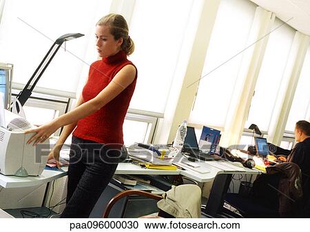 Stock Image - Woman using printer in office. Fotosearch