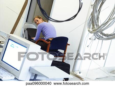 Woman working on laptop computer on chair, cables hanging in foreground View Large Photo Image Stock Image - Woman working on laptop computer on chair, cables hanging in foreground. Fotosearch