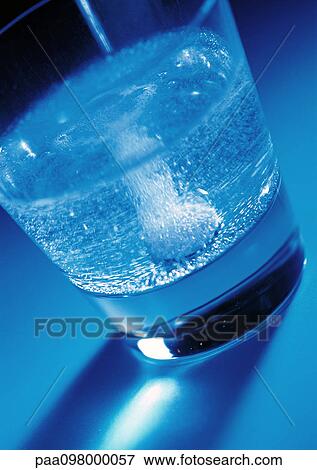 Stock Photo - Glass holding effervescent medicine, close-up. Fotosearch