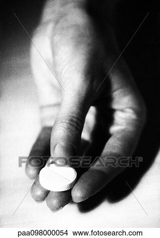 Picture - Hand holding a medicine tablet, B&W. Fotosearch