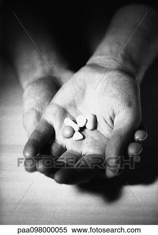 Stock Photography - Hand holding pills in palm, B&W. Fotosearch