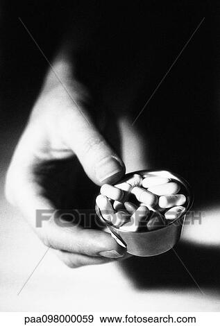 Stock Photo - Hand holding small bowl of pills, B&W. Fotosearch