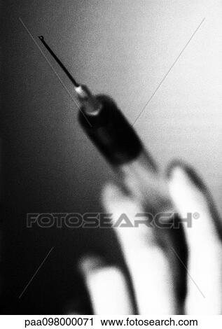 Stock Image - Hand holding syringe, close-up, B&W. Fotosearch