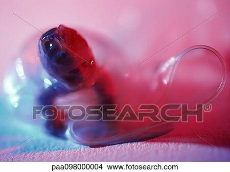 Picture - Plastic baby doll inside a condom, close-up. Fotosearch