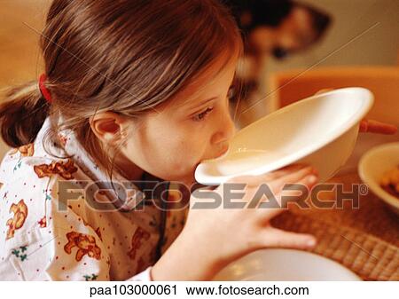 Stock Image - Child drinking from bowl, side view. Fotosearch