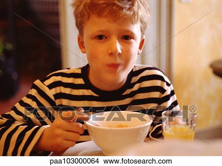 Picture - Child eating cereal, looking at camera, portrait. Fotosearch