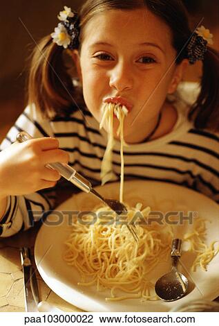 Stock Image - Child eating spaghetti, smiling at camera. Fotosearch