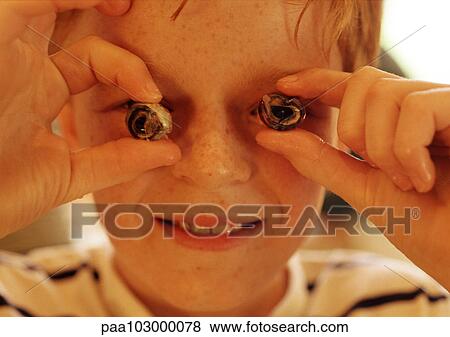 Stock Photo - Child holding escargot in front of eyes, close-up. Fotosearch