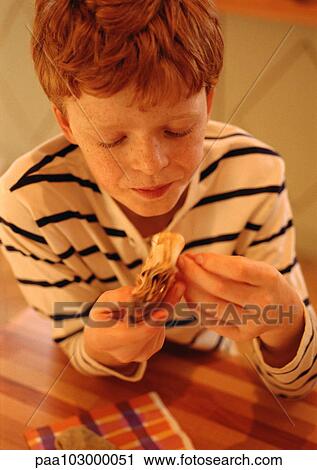Child holding food in hands, looking down, portrait View Large Photo Image Stock Image - Child holding food in hands, looking down, portrait. Fotosearch