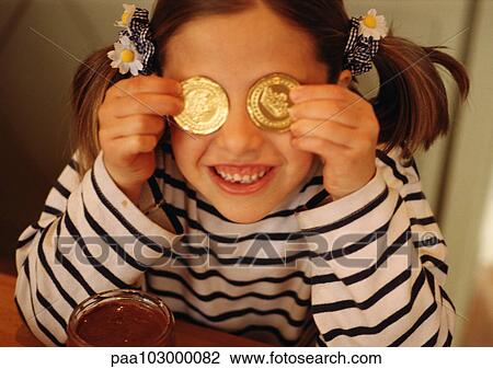 Child holding gold coins in front of eyes, smiling View Large Photo Image Stock Image - Child holding gold coins in front of eyes, smiling. Fotosearch