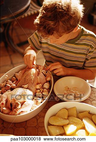 Stock Photo - Child touching raw chicken in casserole dish. Fotosearch