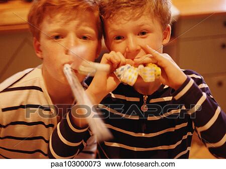 Stock Image - Children blowing noise makers, portrait. Fotosearch